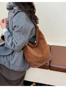 Side view of brown suede and leather shoulder bag with wide strap on model
