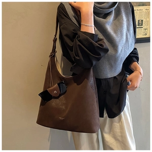 Detailed close-up of dark brown suede tote bag with attached glasses case