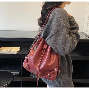 Detail view of burgundy leather bucket bag featuring drawstring closure and metal buckle strap