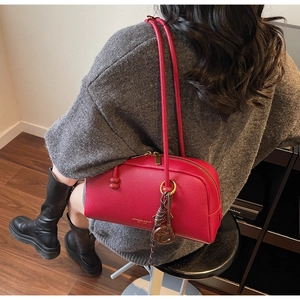 Detail view of red lychee leather pillow bag worn on shoulder by a model in interior