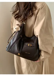 Detail view of brown tote bag featuring gold lettering and a plush bear pendant accessory