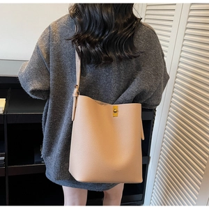 Détail du sac fourre-tout en cuir beige avec fermoir doré et bandoulière réglable chic