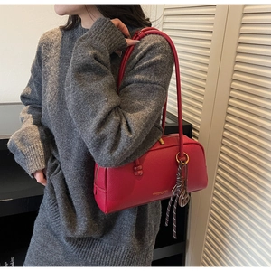 Detail of red litchi leather Boston bag showing side knot and metal ring decoration