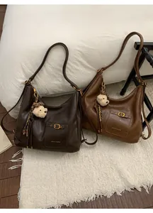 Close-up of vintage leather tote bags with metal buckles and cute bear charms
