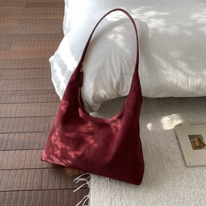 Close-up of a burgundy suede tote bag showing its vintage texture and zipper detail