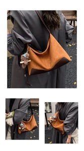 Detail view of caramel brown suede hobo bag with teddy bear charm and leather corners