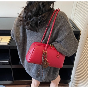 Detail view of red lychee grain leather pillow bag with gold hardware and charm