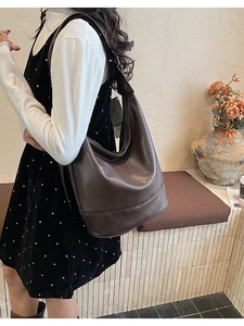 Deep brown leather hobo shoulder bag with matte texture and wide strap on a model