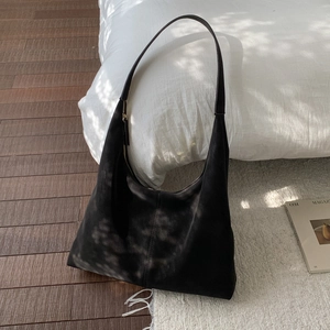 Detail of minimalist black suede hobo bag with vertical stitching and smooth zipper closure