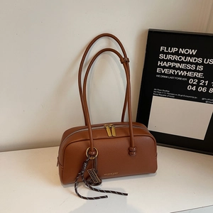 Detail of vintage brown litchi grain leather bag with gold branding and woven strap