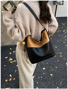 Detail of contrast stitching tote bag with suede texture and floral charm on model