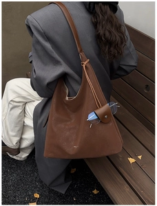 Detail of coffee brown tote bag with leather texture and creative glasses holder feature