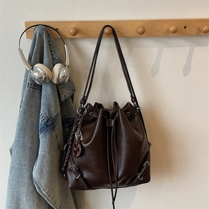 Detail of vintage brown bucket bag with drawstring closure and a pretzel charm on wood