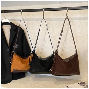 Minimalist suede hobo bags in caramel, black, and brown hanging on a metal rack