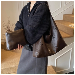 Detail of a large brown laser-cut tote bag with a matching small zipper pouch
