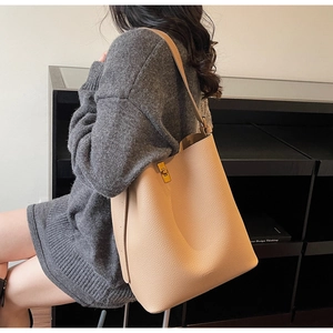 Détail du sac seau en cuir grainé abricot avec fermoir rotatif en métal doré élégant
