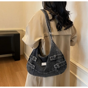 Close-up of a dark grey denim hobo bag featuring silver buckles and rectangular metal plaque