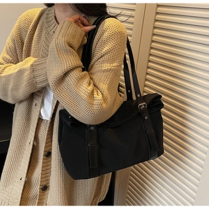 Détails d'un sac à bandoulière en daim noir avec œillets métalliques et lanière