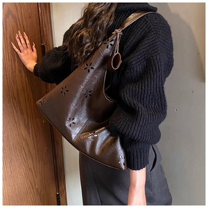 Detailed view of dark brown tote bag with intricate floral laser-cut patterns on faux leather