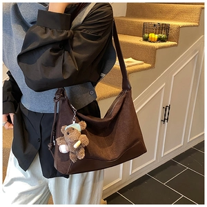 Detailed texture of dark brown suede hobo bag with a cute plush bear pendant