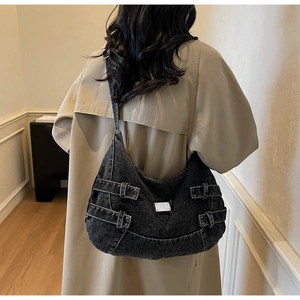 Detail of hobo bag in washed denim with silver buckles and moon shape on a model