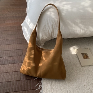 Close-up detail of a caramel suede hobo tote bag featuring minimalist vertical stitching