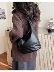 Detail of a black large-capacity leather Hobo bag worn on the shoulder in a casual setting