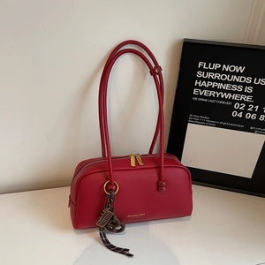 Detailed close-up of red lychee pattern leather pillow bag with gold zipper and charms