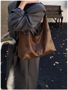 Detailed view of brown hollowed-out tote bag featuring floral laser-cut patterns