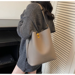 Détail du sac seau en cuir grainé gris avec fermoir doré et lettrage de marque