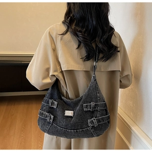 Detail view of large dark grey denim hobo bag featuring silver buckle and metal plaque