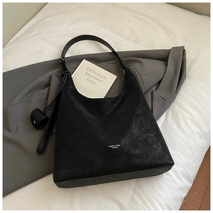 Detail of black matte leather hobo bag with vintage texture and circular charm accessory