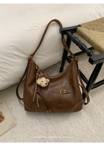 Close-up of a brown leather tote bag with a teddy bear charm and ZSKE PARIS logo detail