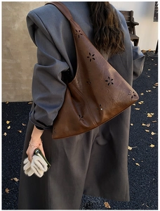 Detailed macro view of laser-cut floral pattern on a brown PU leather shoulder tote bag