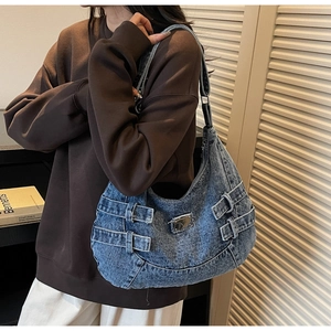 Detail of vintage blue denim hobo bag featuring silver metal buckles and punk style straps