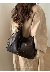 Detail of dark brown tote bag showing the front pocket buckle and brand logo