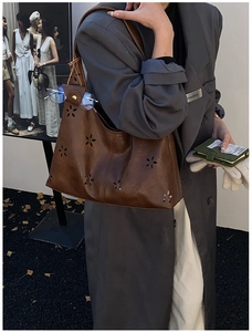 Detail of vintage brown leather bag with laser-cut floral patterns and wide strap