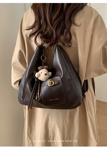 Detail of dark brown retro leather tote bag with gold logo and plush bear charm