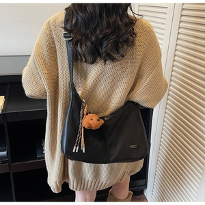 Détail du sac cabas noir en nylon avec pendentif ours et pompon sur la bandoulière