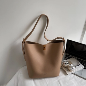 Gros plan sur le cuir grainé et le fermoir pivotant en métal du sac seau couleur camel