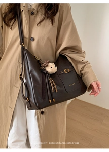Detail of dark brown tote bag with metal buckles and a cute plush bear charm accessory