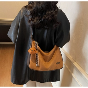 Sac hobo en daim marron avec pendentif ours en peluche et pompon tressé sur l'épaule