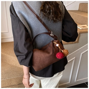 Detail view of brown faux suede underarm bag with decorative colorful plush pompom charms