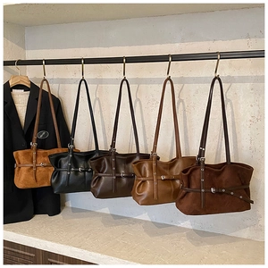 Détail de sacs cabas vintage en cuir mat en cinq tons terreux sur un support métallique