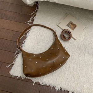 Detailansicht der braunen Halbmond-Hobo-Tasche mit silbernen Nieten und Ersatzriemen