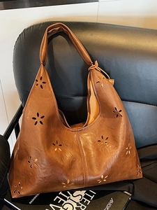 Brown vintage hobo bag with laser-cut floral patterns and textured leather finish