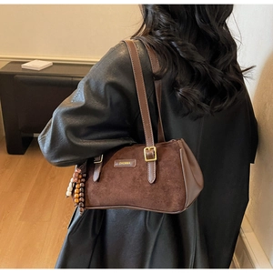 Détail du sac baguette en daim marron avec pendentif à pampilles et bandoulière en cuir