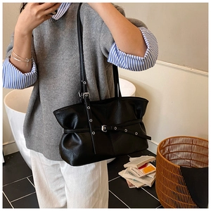 Détail du sac bandoulière en cuir noir avec design plissé et sangle à boucle en métal