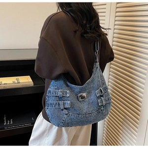 Detail of a large vintage denim tote bag with biker-style side buckles and patch design