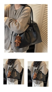 Close-up of black lychee grain tote bag with adjustable buckle and brown bear charm